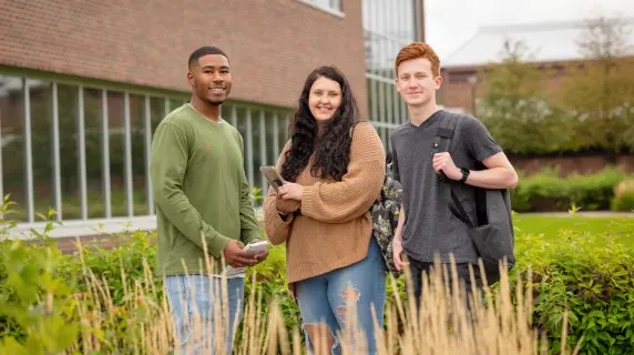 Three students outside a building on NHCC's campus in the fall